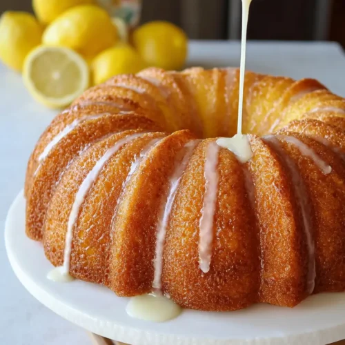 Moist and fluffy Lemon Bundt cake topped with a lemon glaze on a decorative plate.