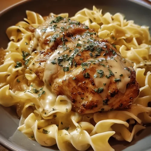 Delicious Chicken with Buttered Noodles served on a plate with herbs.