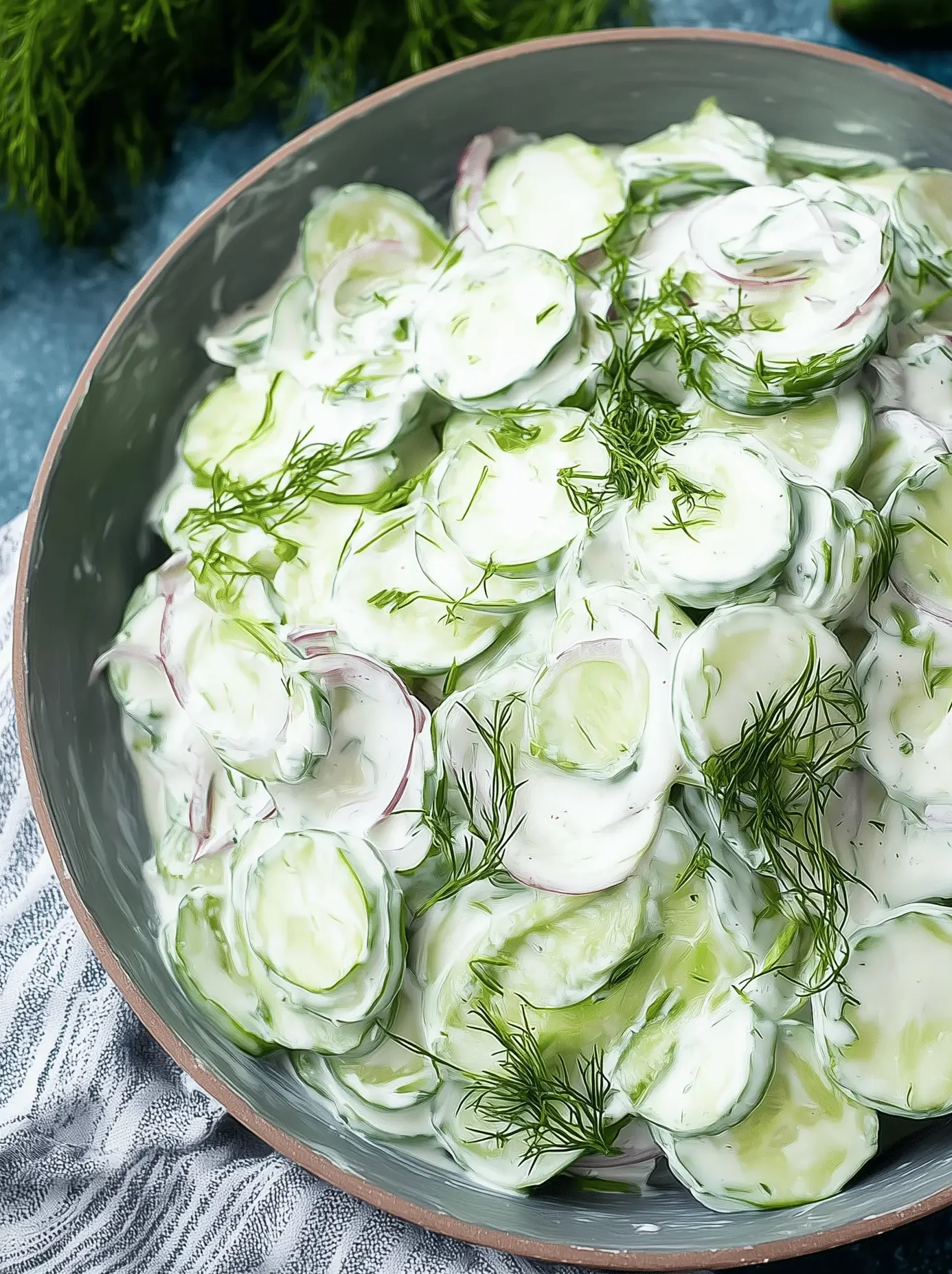 Fresh creamy cucumber salad with dill and red onions in a bowl